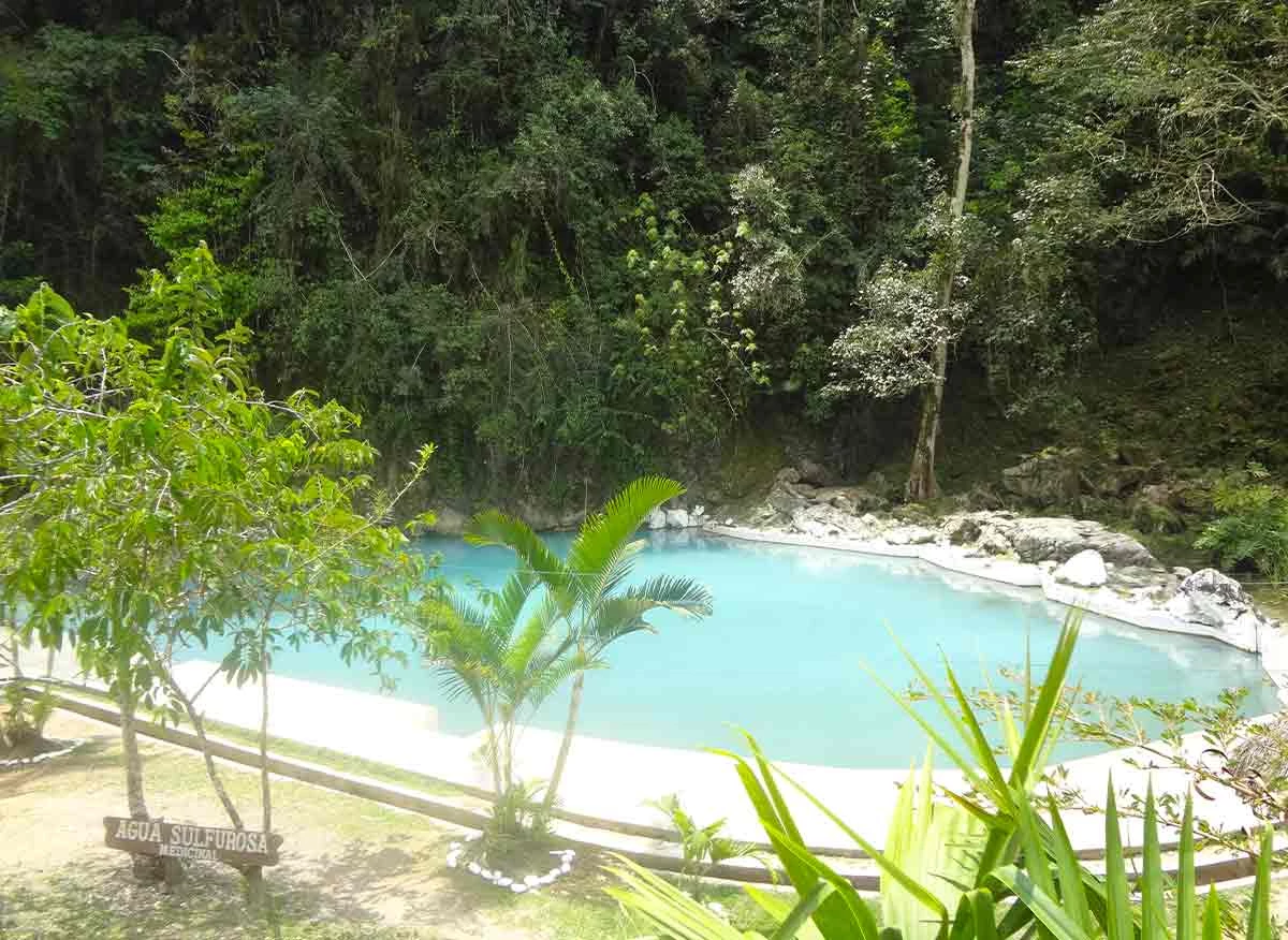 Poza de aguas sulfurosas de color turquesa al pie del cerro, en la ruta a la cueva de Tingo María