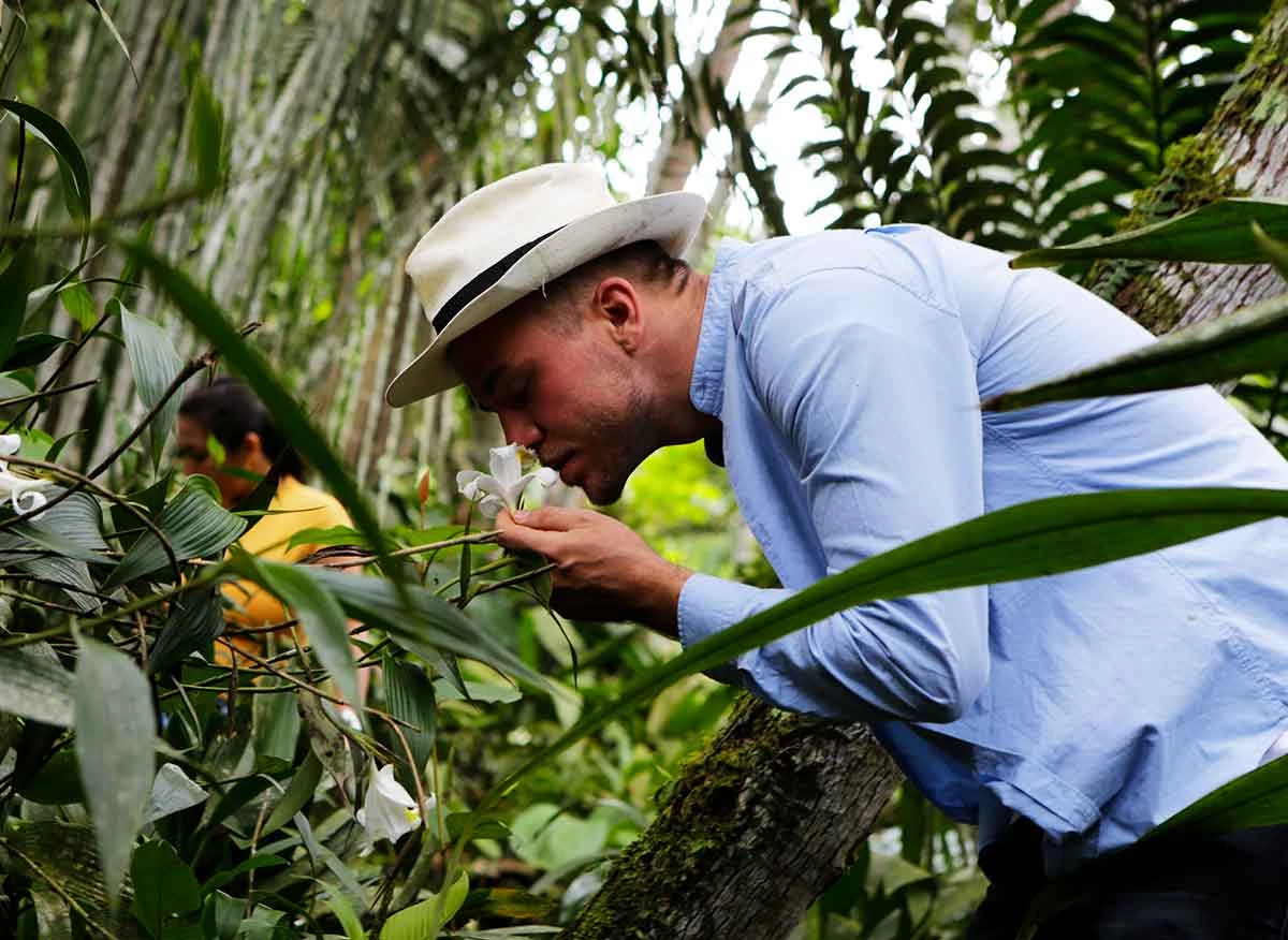 Visitante observando de cerca una orquídea en un vivero de Moyobamba